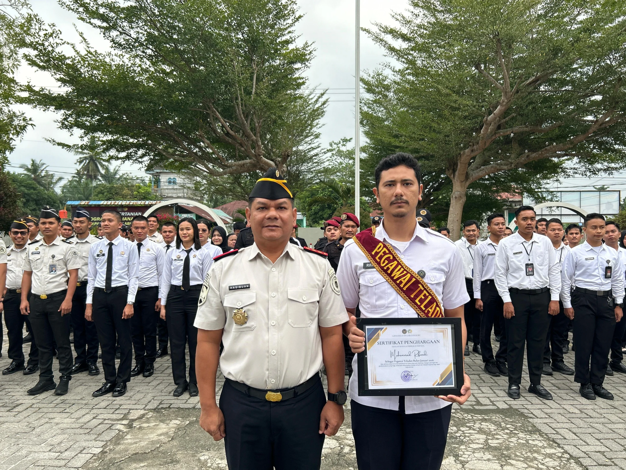 Apresiasi Dedikasi, Kalapas Labuhan Ruku Beri Penghargaan Pegawai Teladan Batubara - Lapas Kelas IIA Labuhan Ruku memberikan piagam penghargaan kepada pegawai teladan yang dinilai memiliki dedikasi dan kinerja tinggi dalam menjalankan tugas, Selasa (3/2). Pemberian penghargaan ini merupakan bentuk apresiasi atas komitmen pegawai dalam mendukung pelaksanaan tugas pemasyarakatan secara profesional dan berintegritas. Penghargaan tersebut diserahkan langsung oleh Kepala Lapas Labuhan Ruku, Hamdi Hasibuan, kepada pegawai teladan periode Januari atas nama Muhammad Rifandi. Kegiatan penyerahan piagam berlangsung di lingkungan Lapas Labuhan Ruku dan disaksikan oleh jajaran pejabat struktural serta pegawai lainnya. Kalapas Labuhan Ruku, Hamdi Hasibuan, dalam sambutannya menyampaikan bahwa penghargaan ini diberikan sebagai motivasi bagi seluruh pegawai agar terus meningkatkan kinerja, disiplin, dan loyalitas dalam menjalankan tugas. Ia menegaskan bahwa keberhasilan organisasi tidak terlepas dari peran aktif dan dedikasi setiap pegawai. Muhammad Rifandi dinilai layak menerima penghargaan tersebut karena menunjukkan etos kerja yang tinggi, tanggung jawab, serta konsistensi dalam menjalankan tugas sehari-hari. Selain itu, yang bersangkutan juga dinilai mampu menjadi teladan dan inspirasi bagi rekan kerja lainnya di lingkungan Lapas Labuhan Ruku. Dengan adanya pemberian piagam penghargaan ini, diharapkan dapat menumbuhkan semangat kompetisi yang sehat serta budaya kerja positif di lingkungan Lapas Labuhan Ruku. Ke depan, pihak lapas berkomitmen untuk terus memberikan apresiasi kepada pegawai berprestasi sebagai bagian dari upaya peningkatan kualitas pelayanan pemasyarakatan.